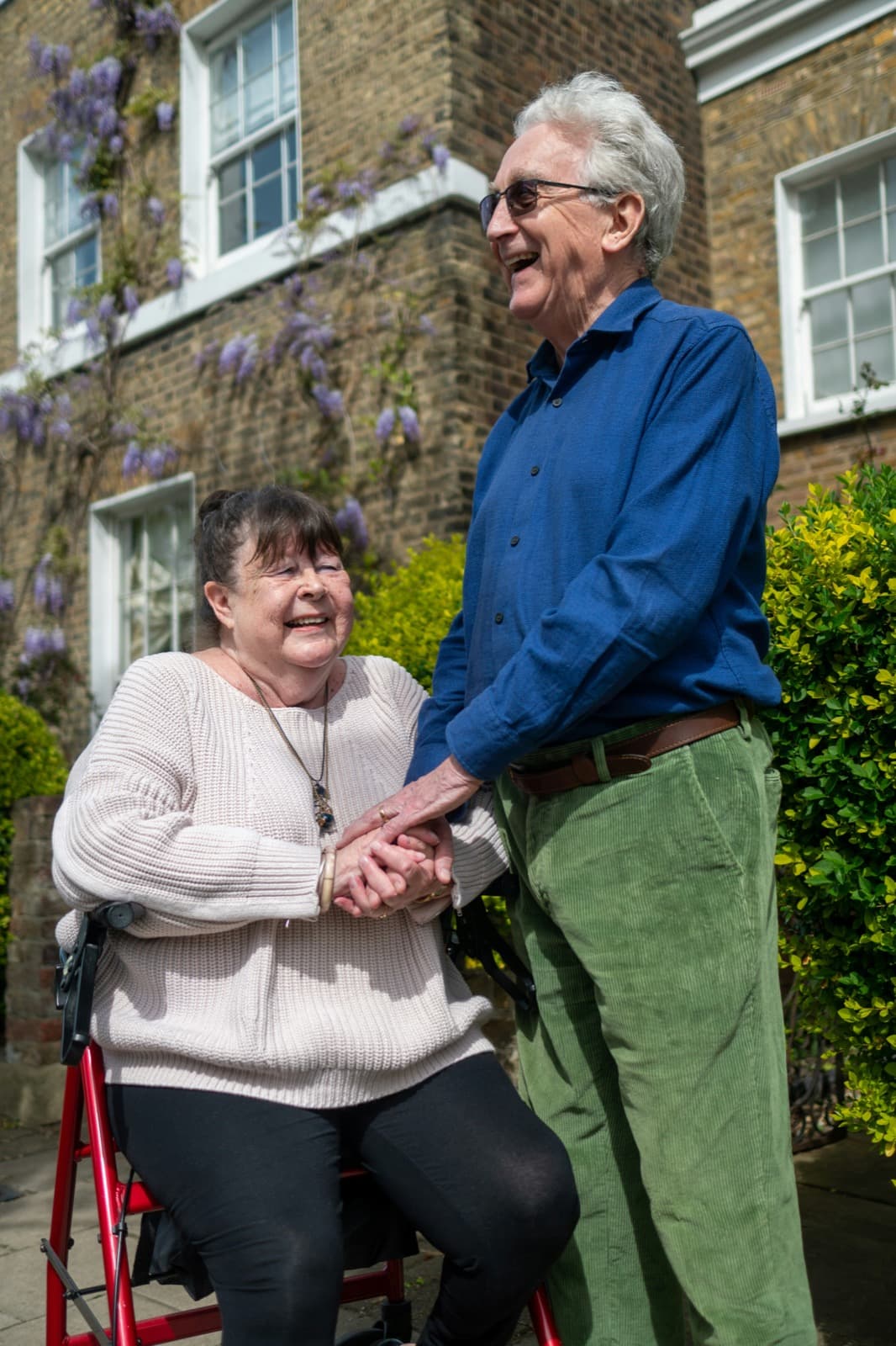 An elderly couple smiling and holding hands outdoors